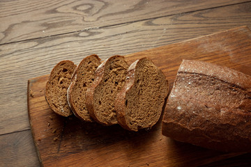 Creative background, freshly baked sliced rye bread on a wooden cutting board, flat lay, copy space. The concept of fresh pastry, black bread.