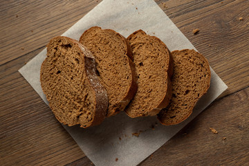 Creative background, freshly baked sliced rye bread on a wooden cutting board, flat lay, copy space. The concept of fresh pastry, black bread.