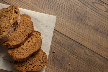 Creative background, freshly baked sliced rye bread on a wooden cutting board, flat lay, copy space. The concept of fresh pastry, black bread.
