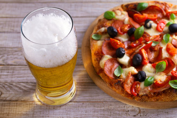 Beer and pizza on wooden plate. Ale and  snack. Horizontal