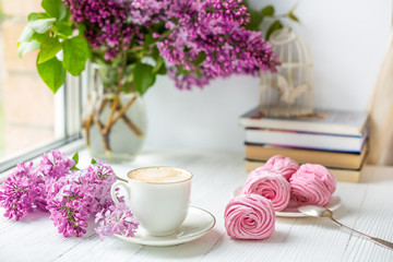 Bouquet of lilacs, cup of coffee, homemade marshmallow. Romantic spring morning. Selective focus