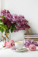 Bouquet of lilacs, cup of coffee, homemade marshmallow. Romantic spring morning. Selective focus