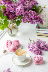 Bouquet of lilacs, cup of coffee, homemade marshmallow. Romantic spring morning. Selective focus