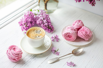 Bouquet of lilacs, cup of coffee, homemade marshmallow. Romantic spring morning. Selective focus