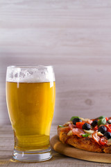 Beer and pizza on wooden plate. Ale and  snack. Vertical