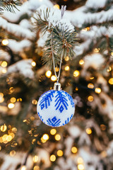 Blue white christmas ball on fir tree branch close up golden yellow light bokeh background