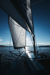 Sail boat with set up sails gliding in a sea or river at sunset