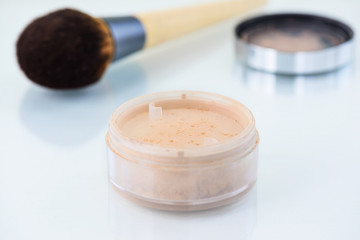 Loose powder with a brush on the table. Face makeup.