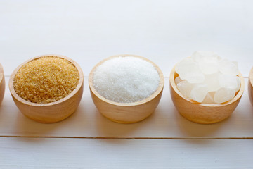 Various types of sugar on wooden background.