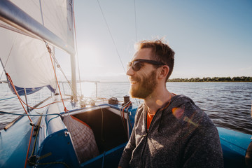 Man dressed in casual wear and sunglasses on a yacht. Happy adult bearded yachtsman close-up...