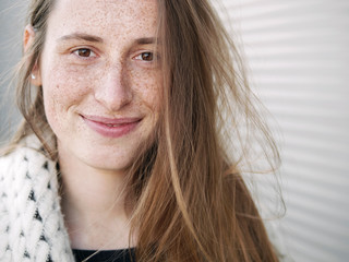 Young trendy dressed serious caucasian woman posing outdoor on urban city blurred geometric background cold season