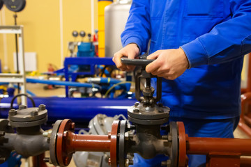 Production worker operates valve on pipeline