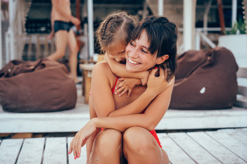 Young mother giving daughter piggyback ride on the beach