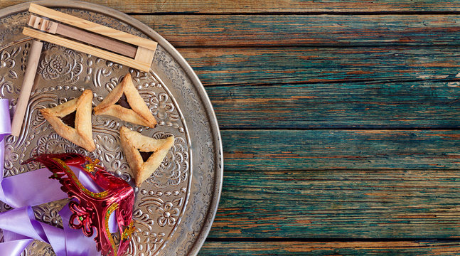 Jewish purim Hamantaschen homemade biscuits or cookies with purim mask and purim gragger. Top view or overhead composition with copy space