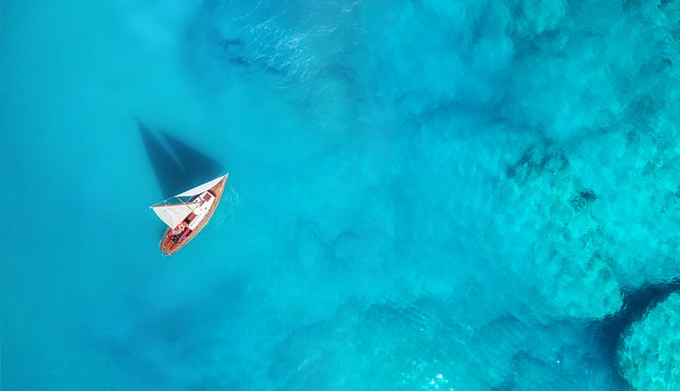 Fototapeta Yacht on the water surface from top view. Turquoise water background from top view. Summer seascape from air. Travel concept and idea