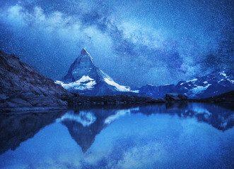 Matterhorn and reflection on the water surface at the night time. Milky way above Matterhorn,...