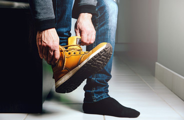 Putting shoes in the hall, preparing for the exit. The man puts on a foot a brown shoe. The concept...