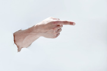 man hand breaking through the paper and pointing to a copy of th