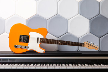 Orange electric guitar laying on piano