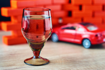  Drunk driving car crash accident. Don't drive after drink concept. Shot glass and a broken car