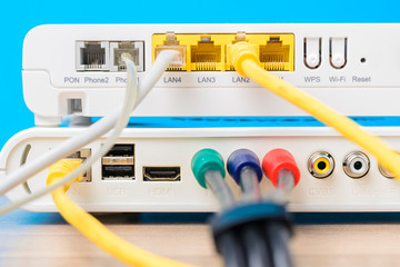 home wireless router with ethernet cables plugged in on blue background, closeup