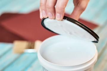 hand open a can of white paint and wooden boards preparing for painting