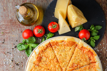 Italian pizza and ingredients on a wooden background, top view
