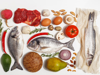 Healthy food clean eating selection: fruit, vegetable, seeds, fish, meat, leaf vegetable on white background. Top view.