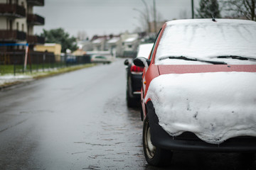 Obraz premium Red car covered with snow along the road. Concept of winter, snowfall