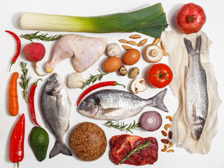 Healthy food clean eating selection: fruit, vegetable, seeds, fish, meat, leaf vegetable on white background. Top view.