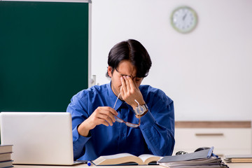 Young male teacher in front of chalkboard  