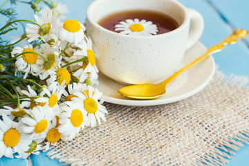 cup of herbal chamomile tea with fresh daisy flowers on wooden background 