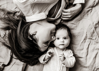 Mother and a little child lying down on bed background . Image in black and white color style