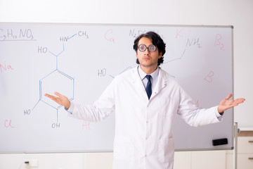 Young funny chemist in front of white board 