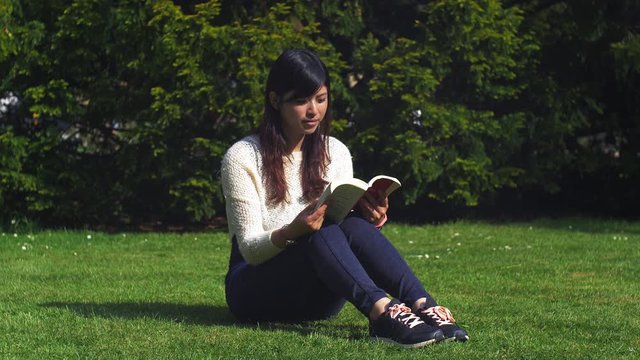 Asian Friend Reading A Book At The Park