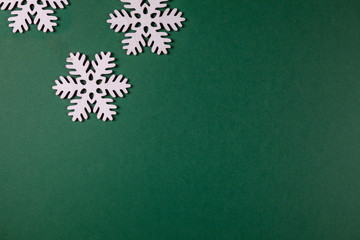 Weiße Schneeflocken aus Holz vor einem grünen Hintergrund mit Textfreiraum. Winterliche Dekoration 