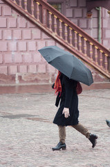 portrait of woman with umbrella Crossing a cobblestone square in the city