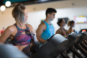 Group of people training on treadmill in gym indoors club. Blinde beauty 20s woman in foreground