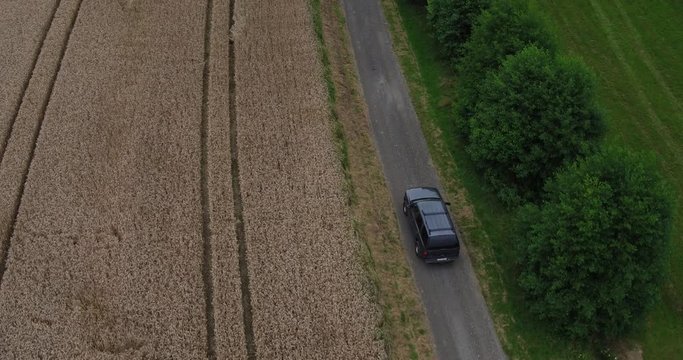 Aerial of an american SUV car driving in rural landscape throuh corn fields on a bright sunny day in bavaria germany 