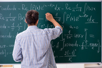 Young male student studying math at school