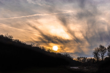 Sunset with dramatic sky with clouds and silhouettes of trees