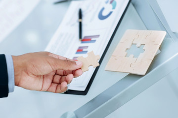 closeup. the businessman is a puzzle,sitting behind a Desk.