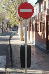 Spanish traffic sign, indicates prohibited direction for vehicles, red circular sign with white horizontal line. Image taken with daylight.