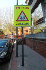 Spanish traffic signal, which indicates caution by the proximity of a school, having children nearby, the signal is fluorescent yellow, taken by day.