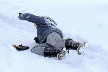 Eine Frau ist auf einer schneebedeckten glatten Straße ausgerutscht und hingefallen 