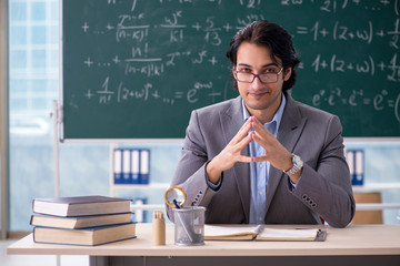 Young handsome math teacher in classroom 