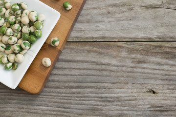 Spicy wasabi snack on white plate, isolated on wooden background