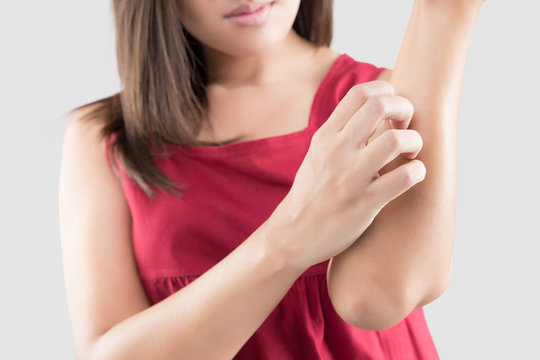 Asian women in the red wear are scratching their arms due to itching on a gray background. Female has an itching arm. The concept of allergy symptoms and healthcare