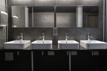 Faucets with washbasin in public restroom in grey colors - 242063167