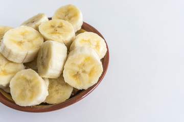 Bowl with banana slices on white background